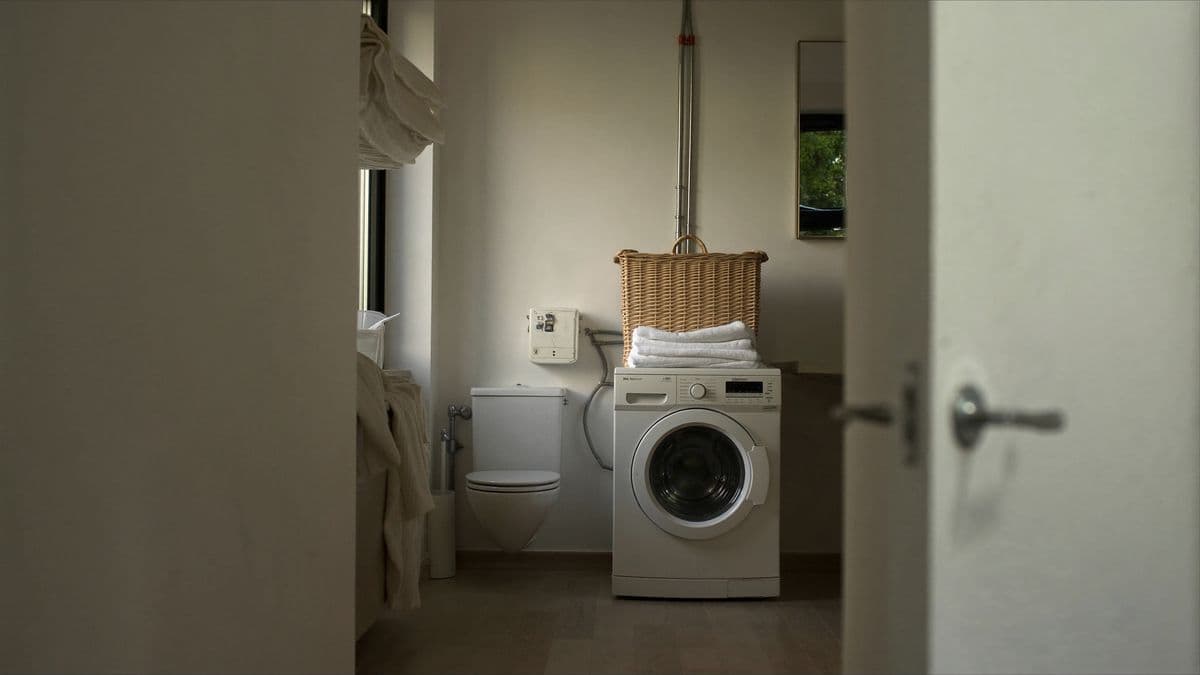 Wasmachine en toilet naast elkaar in een lichte Nederlandse bijkeuken